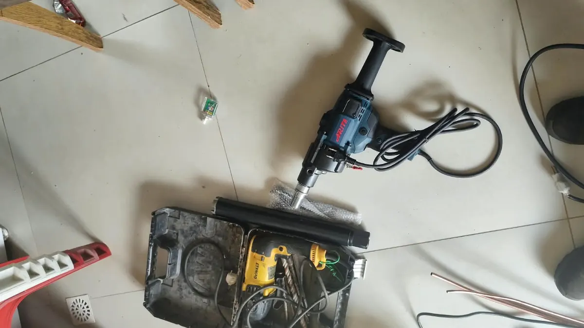 Caixa elétrica aberta no chão, com furadeira e fios ao lado durante um reparo
